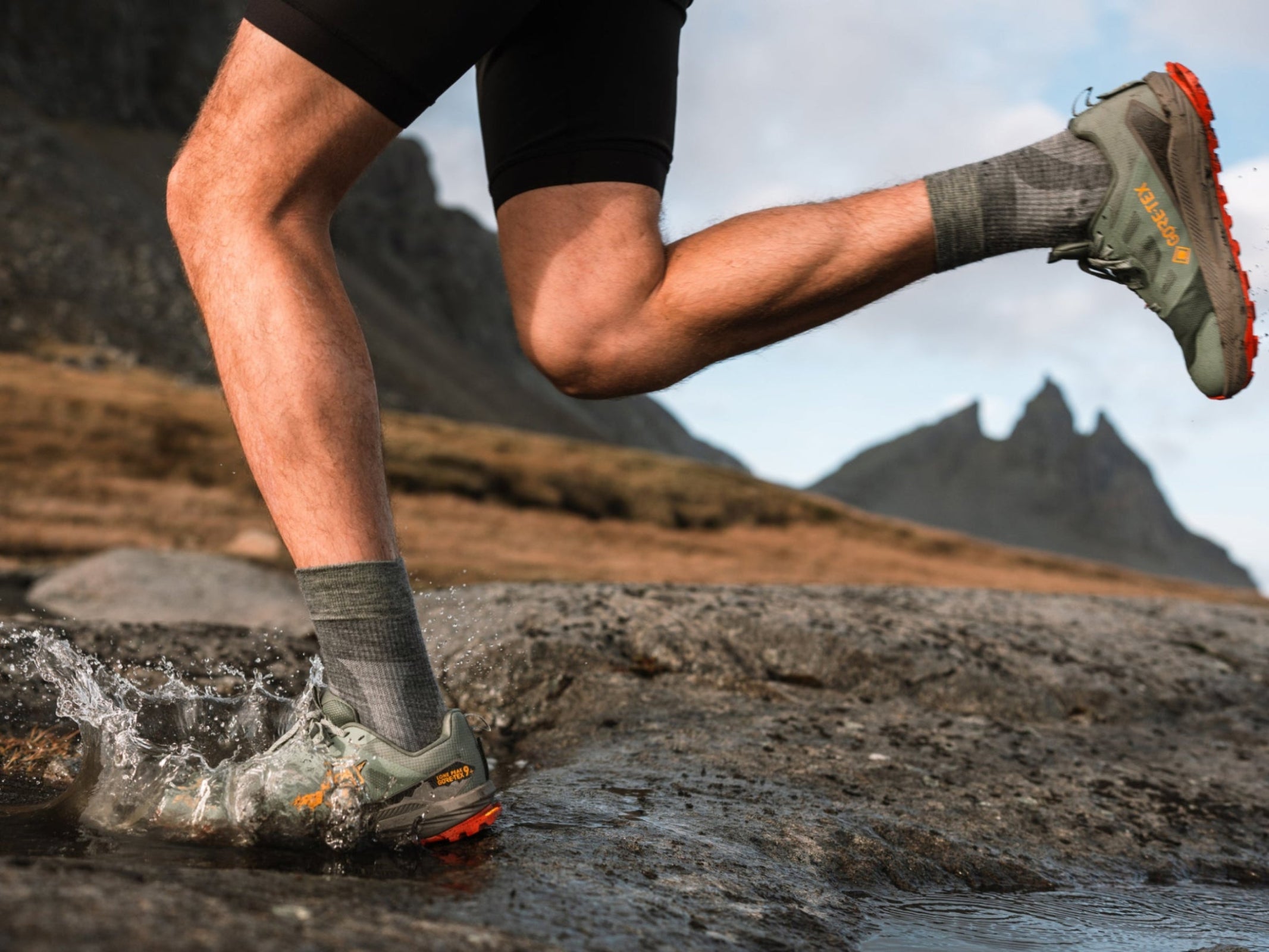 Person running on a rocky trail with mountains in the background